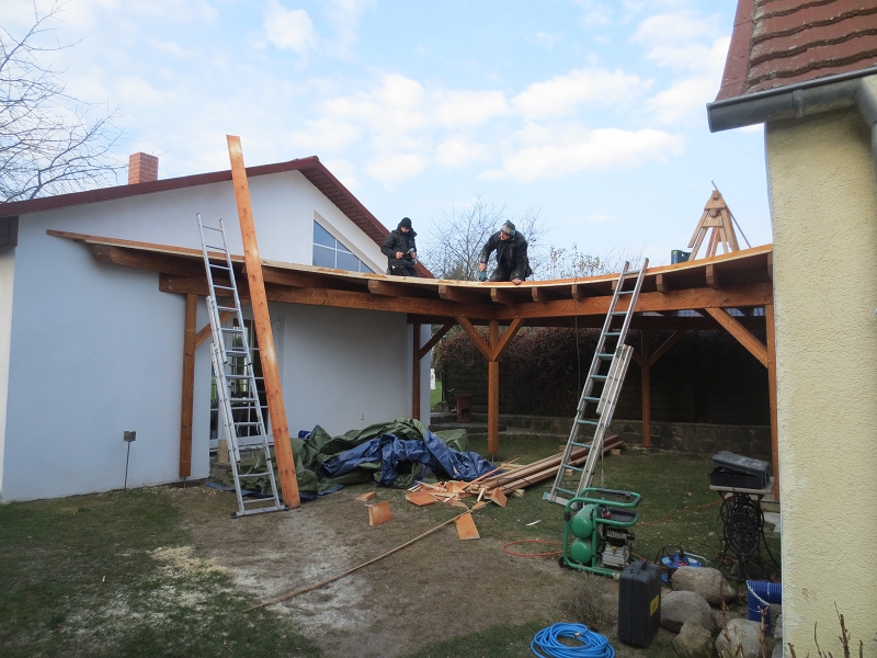 Wir können auch geschwungen. Zwei Kollegen passen die Holzsegmente der Begrenzungsbohle an die Dachlinie an.